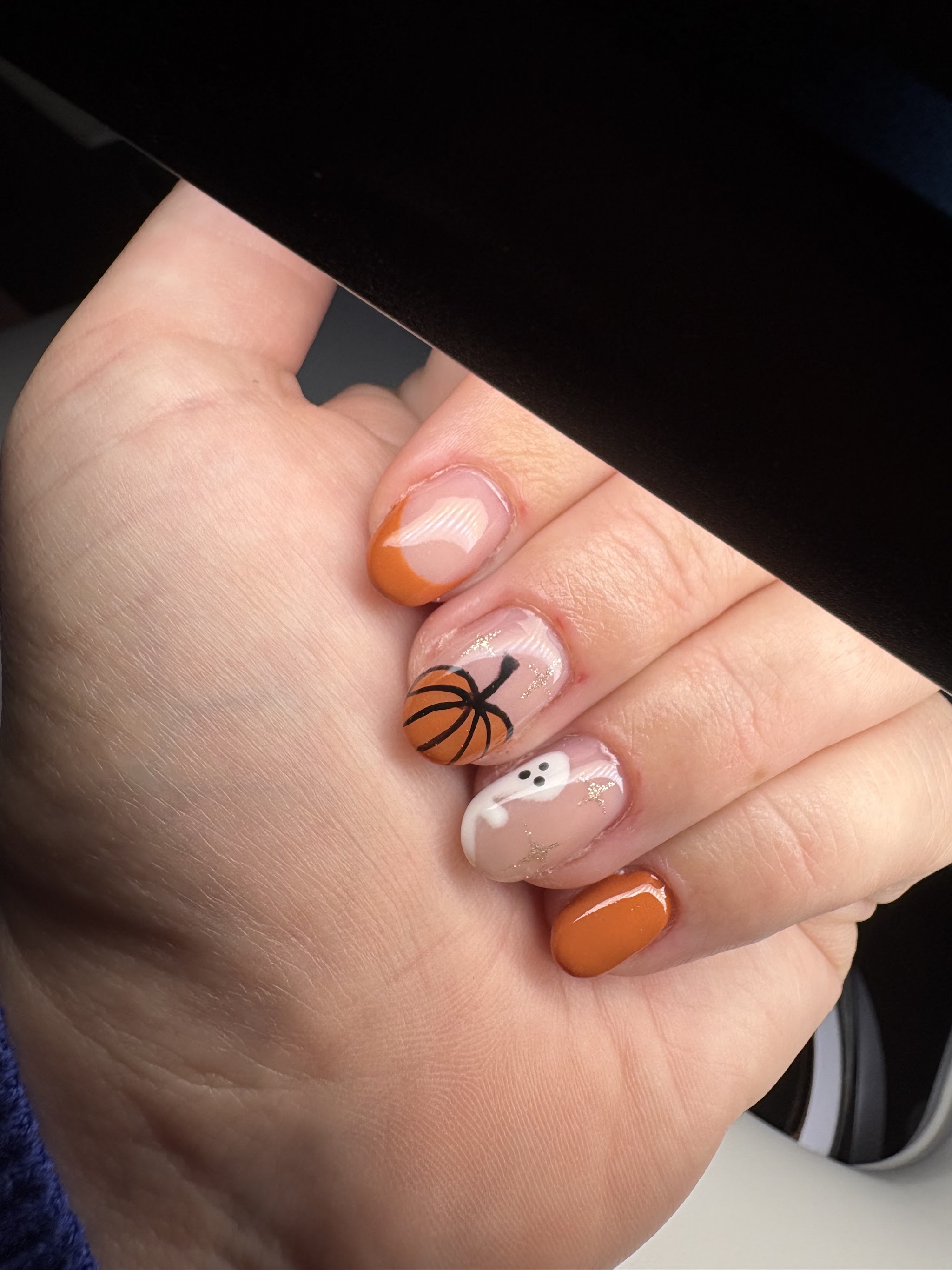 Oranje nagels met een handgetekende pompoen en een spookje